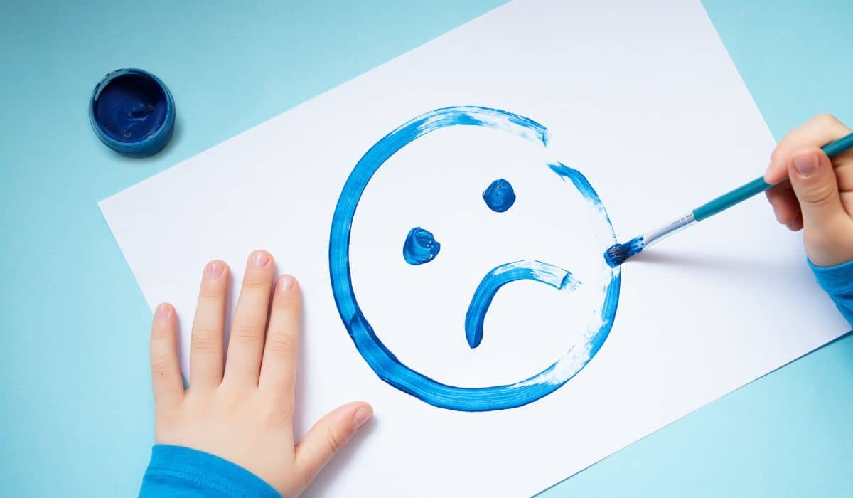 person painting a sad face on paper